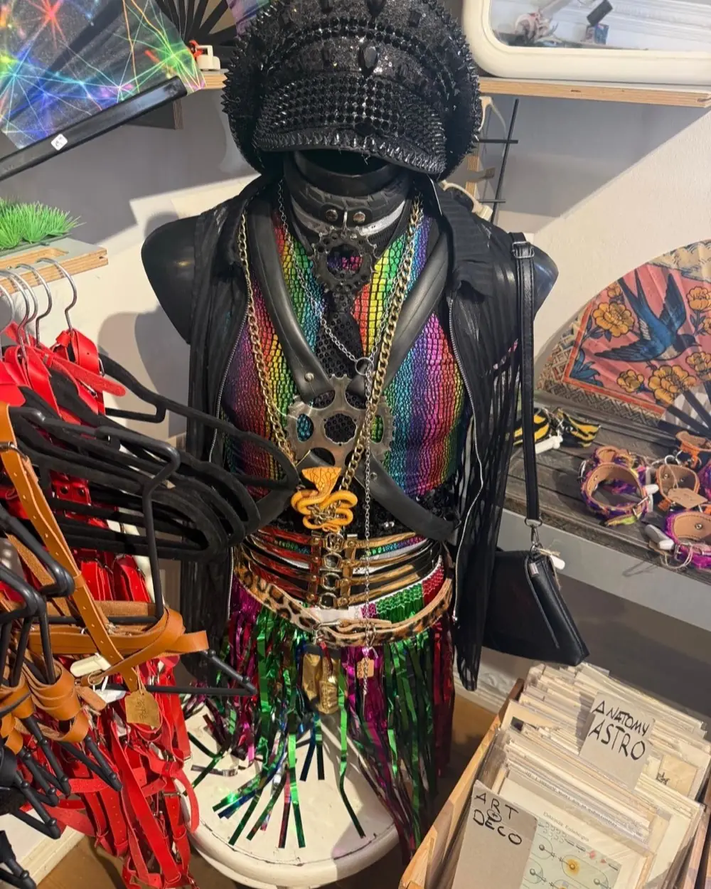 Büste mit Regenbogen-Top, Fahrradketten-Schmuck, Nieten-Mütze und Fransenrock